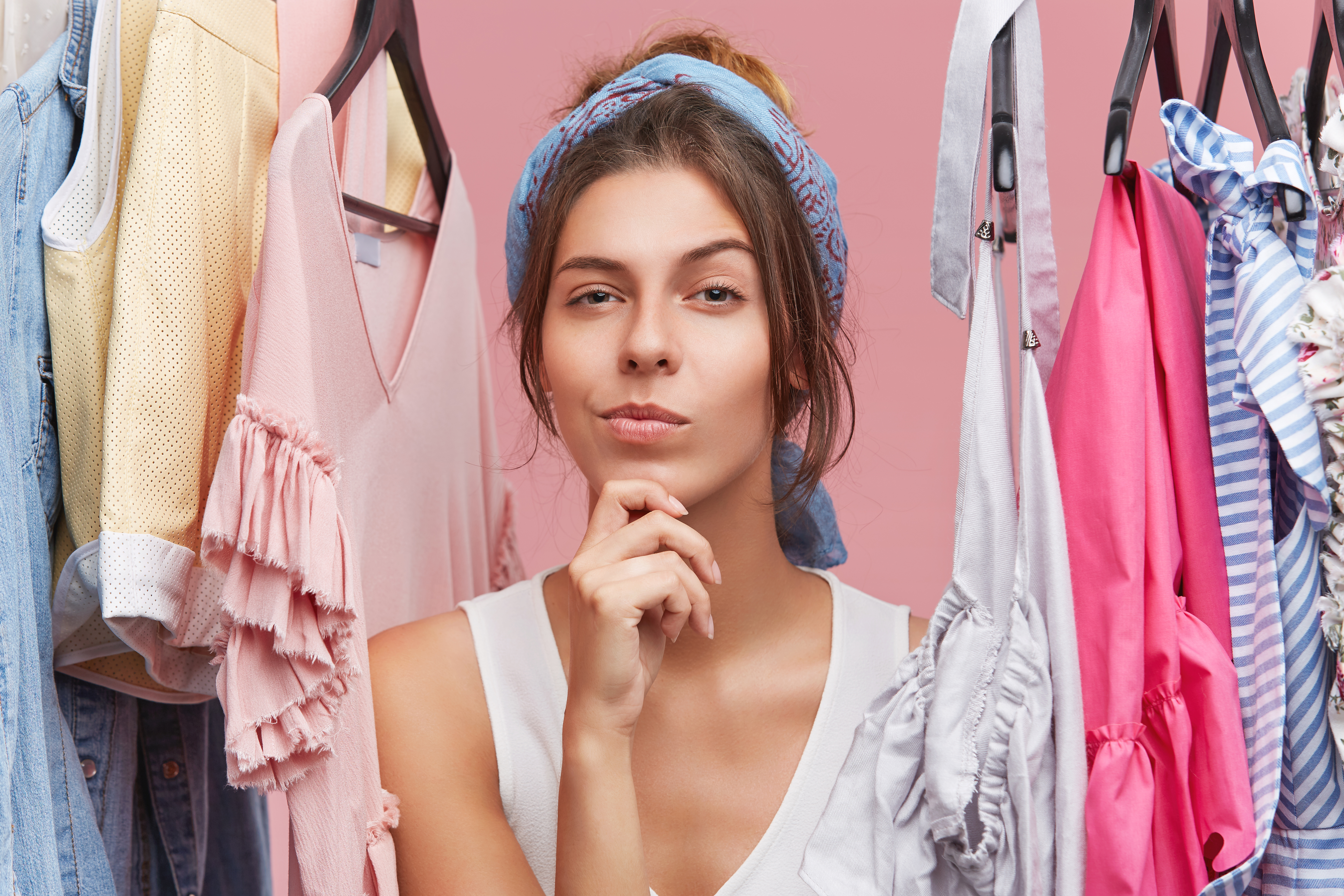 Woman raises a brow as she stands amidst clothing | Source: wayhomestudio on Freepik