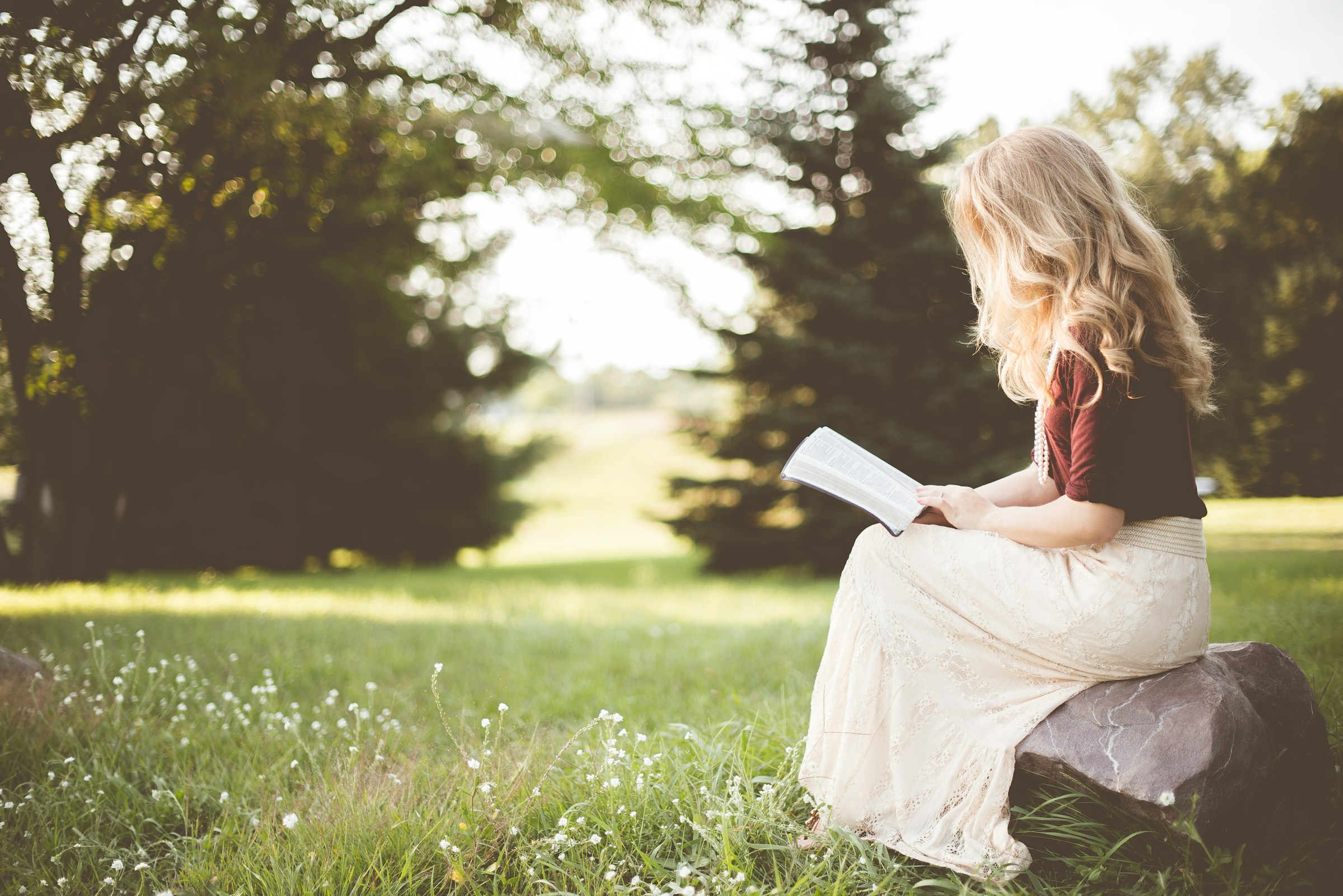 A woman sitting on a rock and reading a book | Source: Unsplash