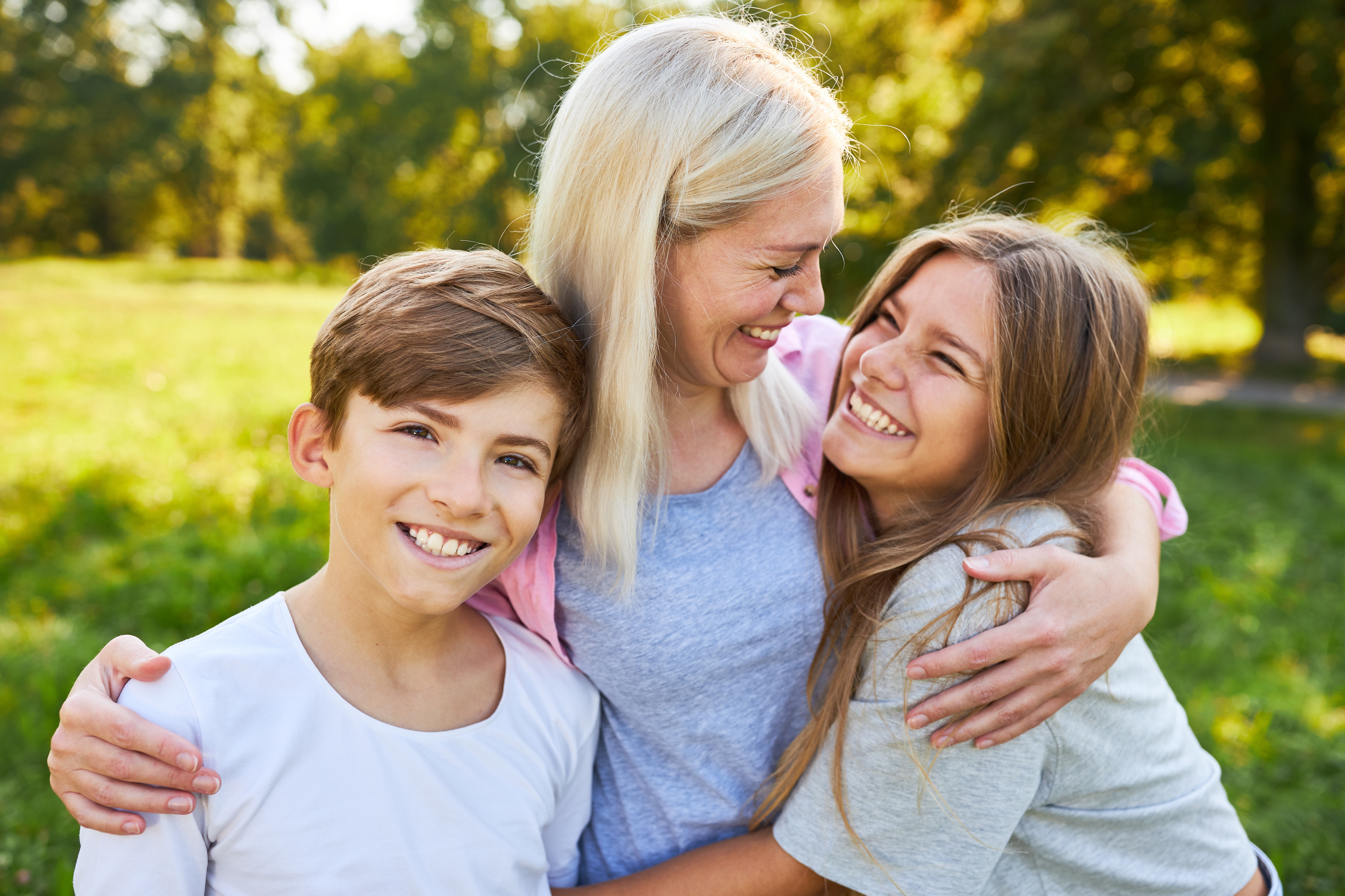 A mother hugging her son and daughter | Source: Shutterstock