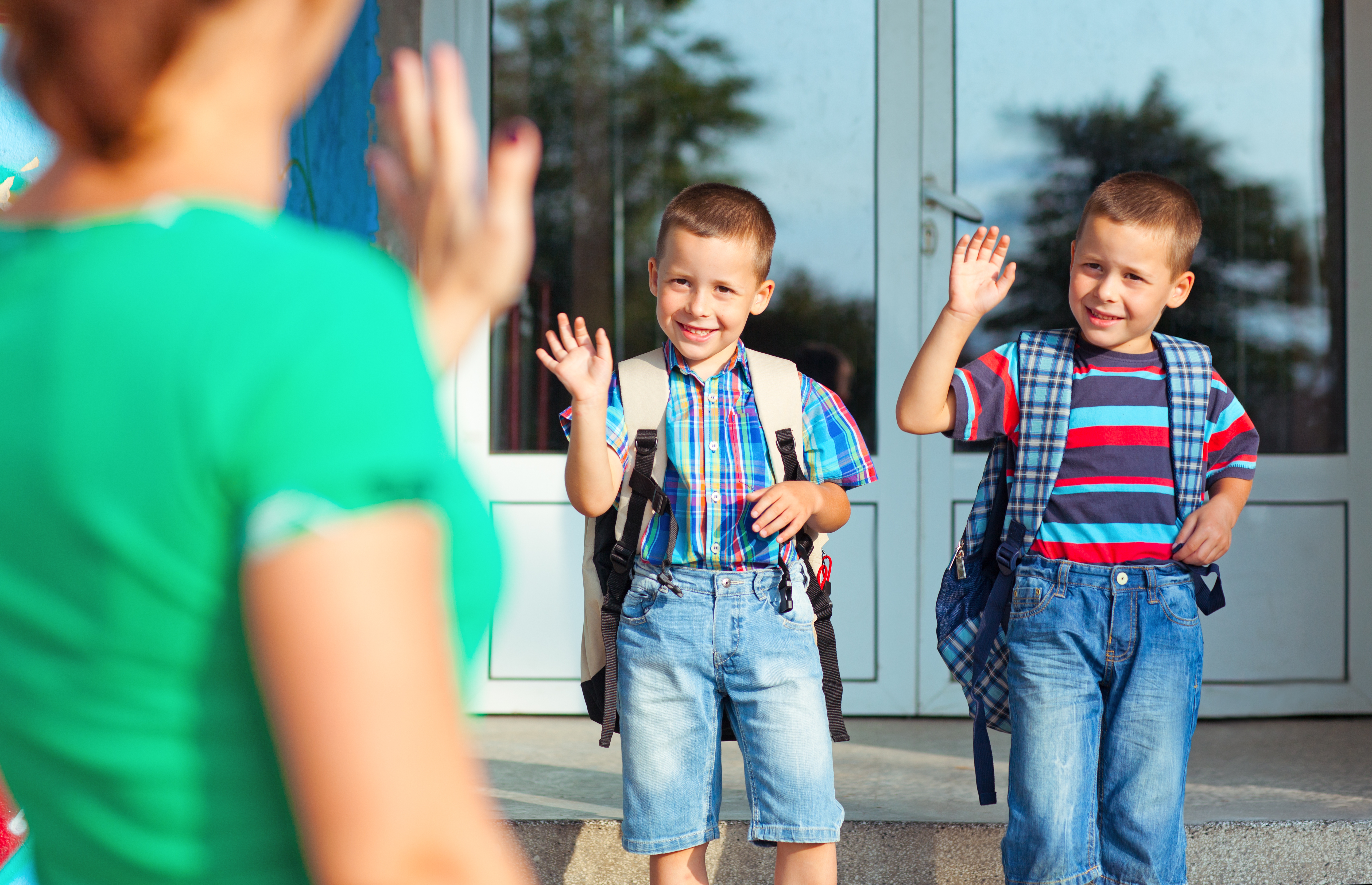 A mother waving to her twin sons | Source: Shutterstock