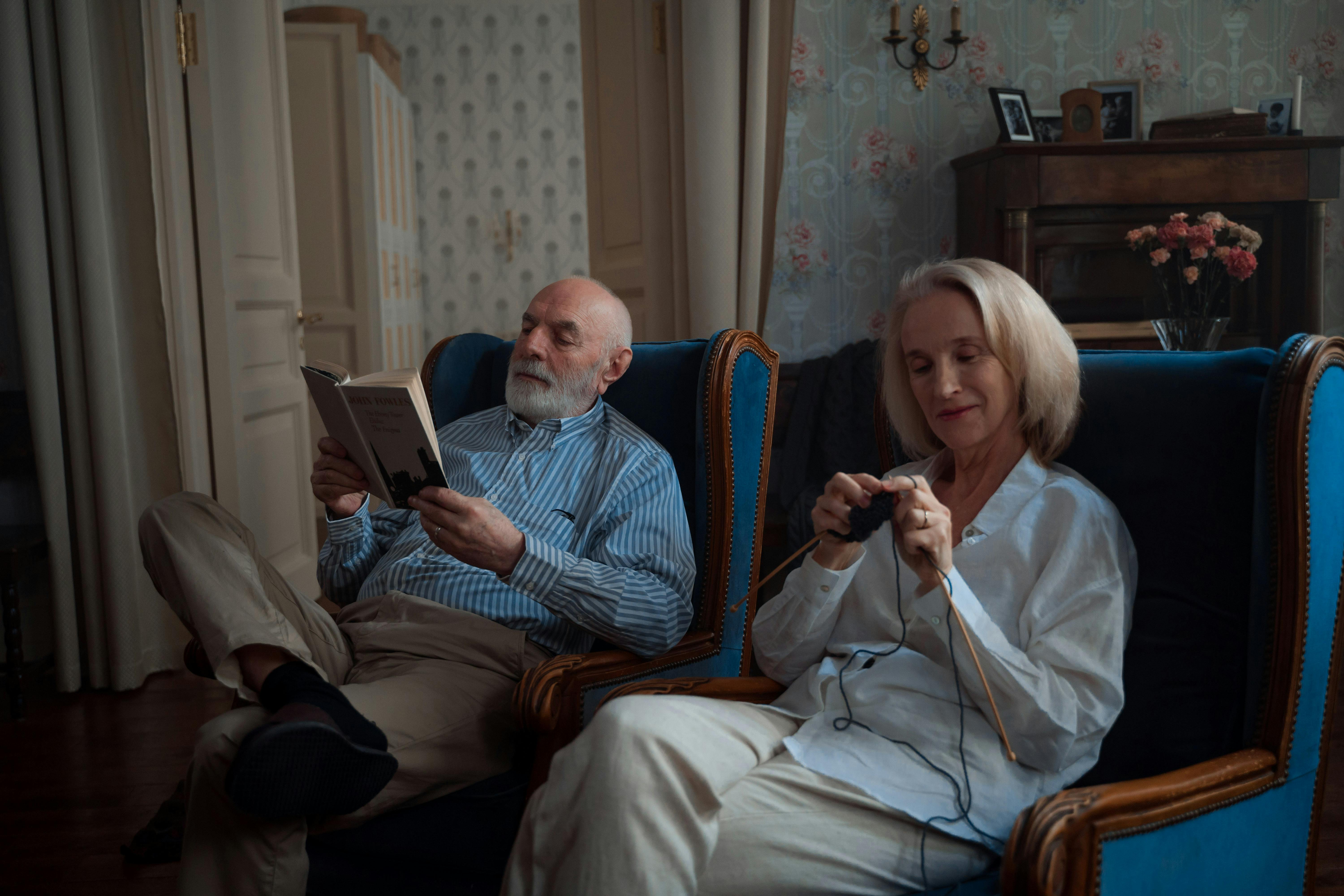 A man reading a book while his wife knits happily | Source: Pexels