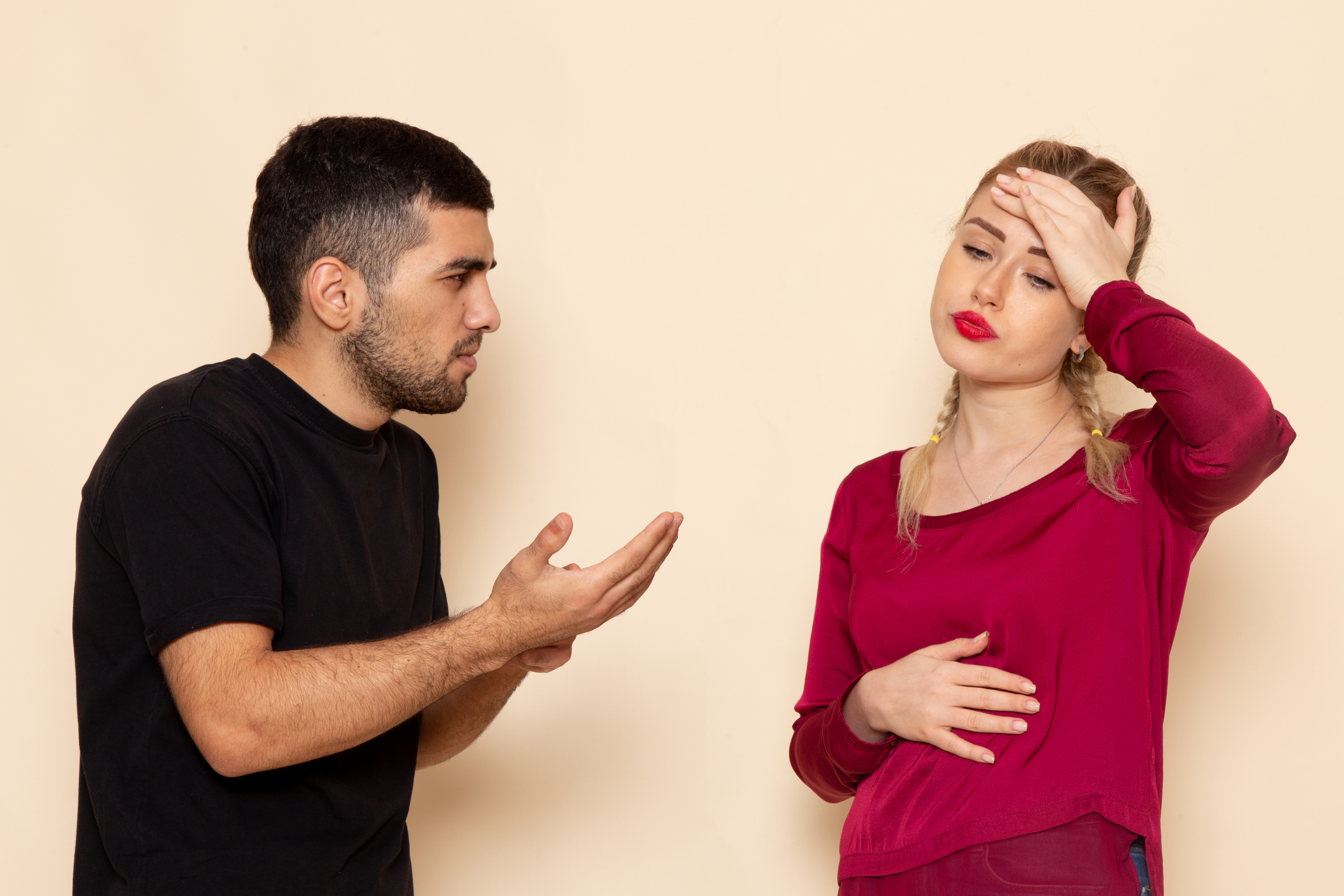 Man gesturing to a woman whose hand is on her forehead | Source: KamranAydinov on Freepik