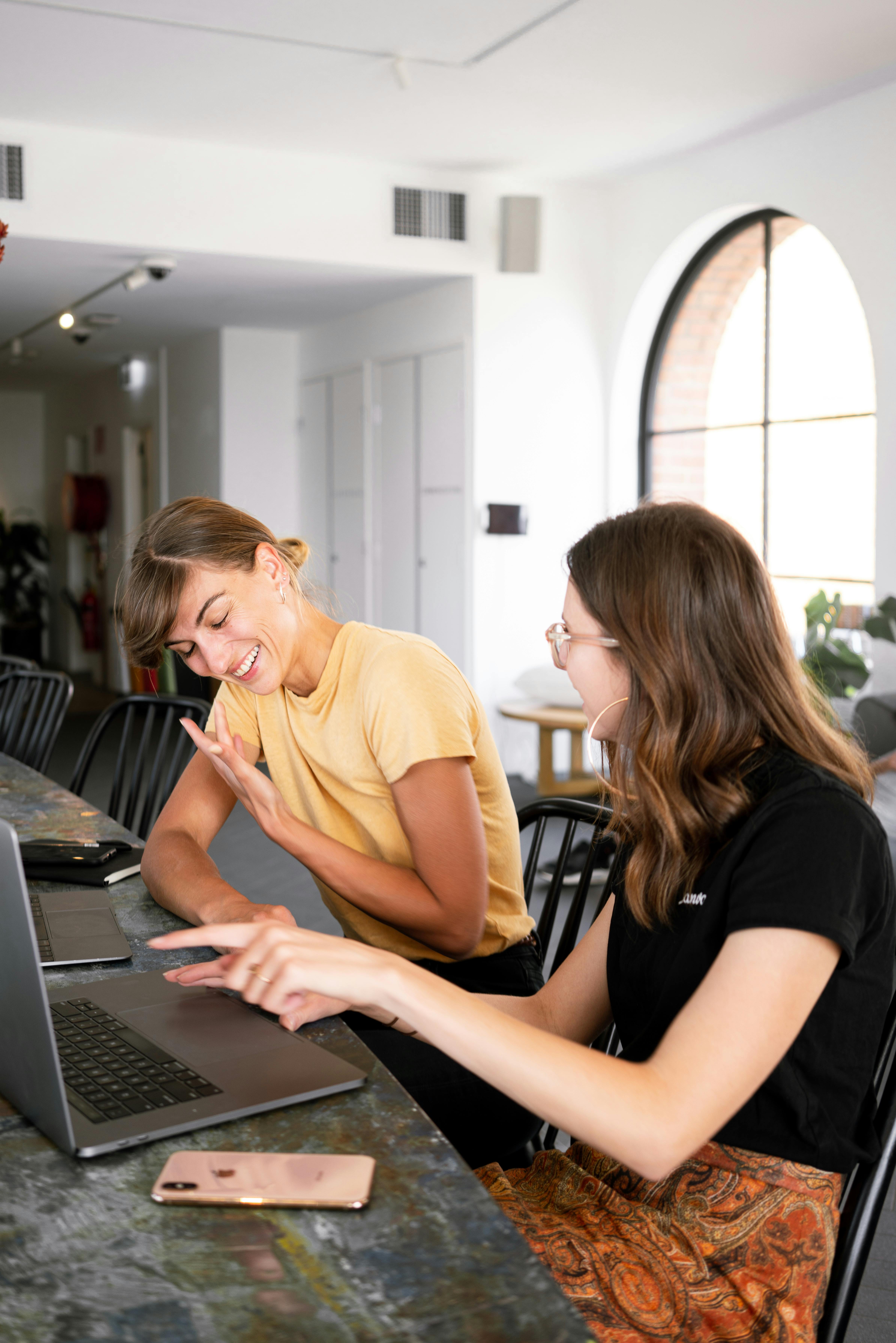 Two women laughing while working on laptops | Source: Pexels