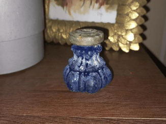 Found this piece in rubbles of an old house. It’s made of glass and fairly heavy. Bottom flat. Top made of metal with a square hole! What is it?