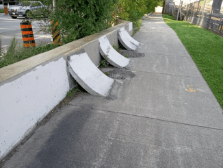 These concrete objects on the sidewalks are fixed to a short wall. This is in Toronto.